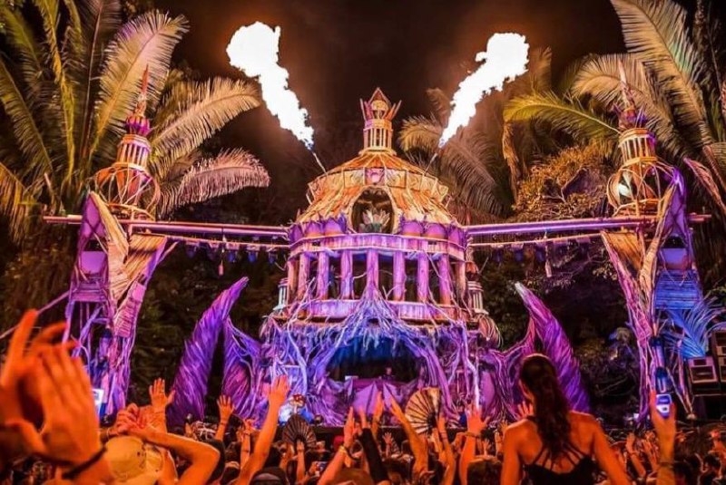 Monumental driftwood stage with pyrotechnics erupting during a live festival